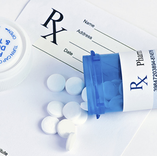 close up image of a prescription bottle spilled out on top of an RX pad of paper.