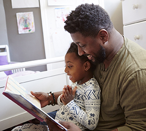 Man reading a book to a young child.
